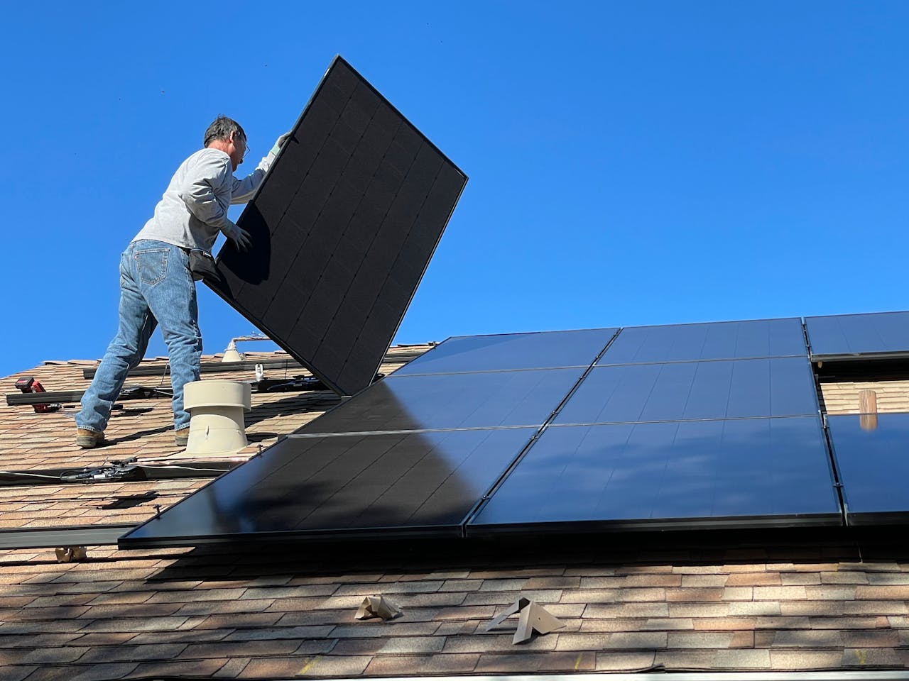 A worker installs solar panels on a sunny day, highlighting renewable energy solutions.